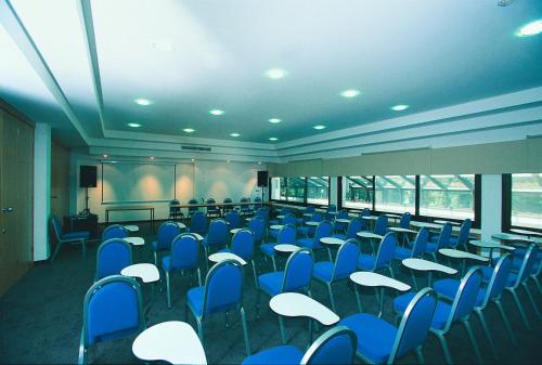a conference room with blue chairs and tables and a screen at Hotel Flores in Poreč