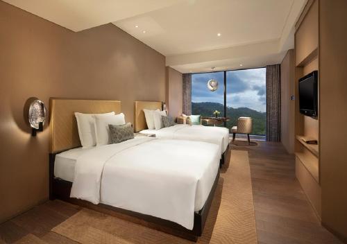 two white beds in a hotel room with a television at Grand Bay Hotel Zhuhai in Zhuhai