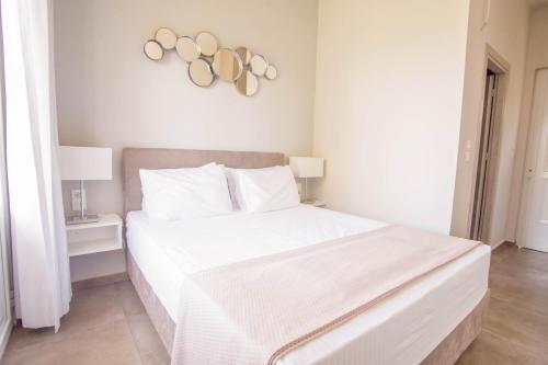 a white bedroom with a white bed with a white bedspread at Teatro Deluxe Rooms in Kato Rodini