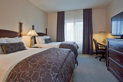 a hotel room with two beds and a desk and a television at Staybridge Suites Tucson Airport by IHG in Tucson