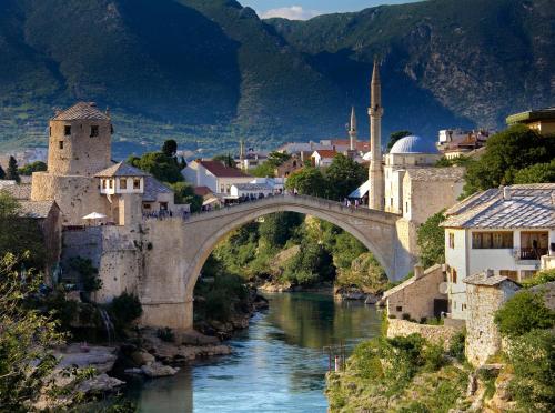 a bridge over a river with buildings and a mosque at MFS Apartments in Mostar