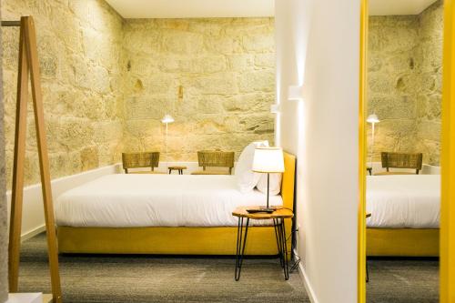 a bedroom with two beds and a stone wall at BO - Álvares Cabral GuestHouse in Porto