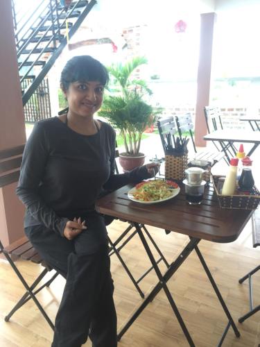 a woman standing next to a table with a plate of food at Sunshine Homestay in Phong Nha