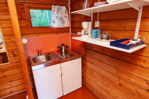 a kitchen with wooden walls and a sink at Rauhalahti Holiday Cottages in Kuopio