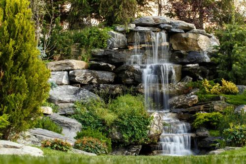 a waterfall in a garden with rocks at Hotel Helen in Bacău