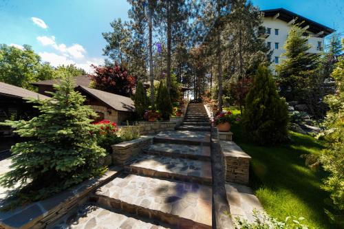 a garden with a pathway with trees and bushes at Hotel Helen in Bacău