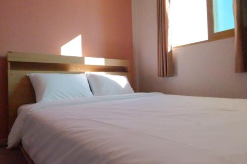 a bedroom with a white bed with a window at Hostel Espace in Chuncheon