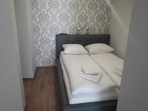 a bed with white sheets and two pillows at Apartament Centrum in Mikołajki