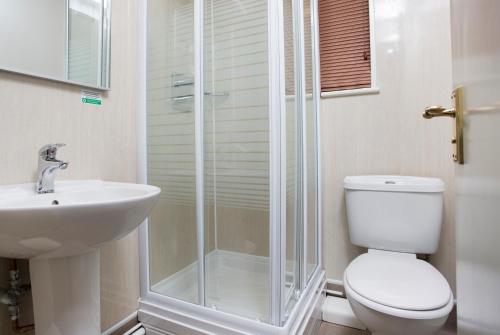 a bathroom with a shower and a toilet and a sink at Breckland Lodge in Attleborough
