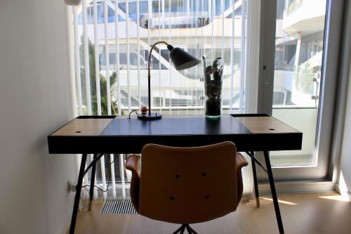 a desk with a lamp and a chair in front of a window at Ocean View Apartment in Aarhus