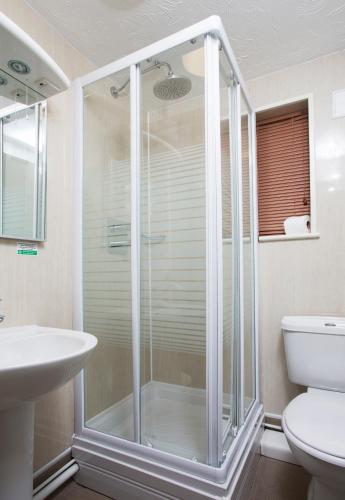 a shower in a bathroom with a sink and a toilet at Breckland Lodge in Attleborough