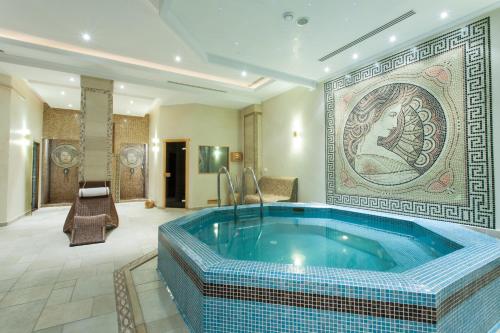 a hot tub in a room with a mosaic wall at Hotel Helen in Bacău