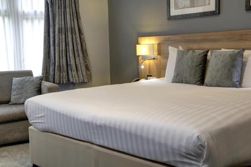a bedroom with a large bed and a couch at Linton Lodge a BW Signature Collection Hotel in Oxford