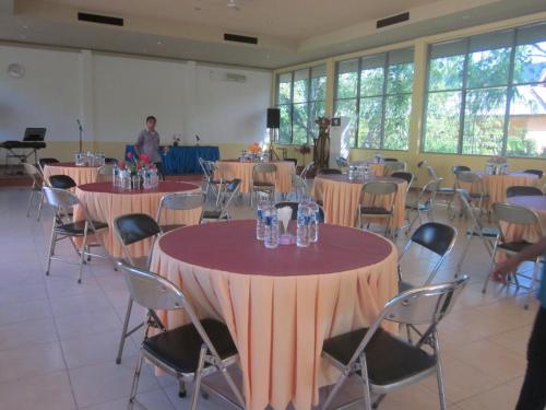 a room with tables and chairs and a man in the background at Hotel Wailiti in Maumere