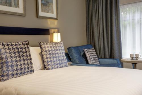 a hotel room with a bed and two blue chairs at Linton Lodge a BW Signature Collection Hotel in Oxford