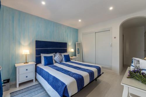 Un dormitorio con una cama azul y blanca y una ventana. en Suites @ Portarade, en Ferragudo