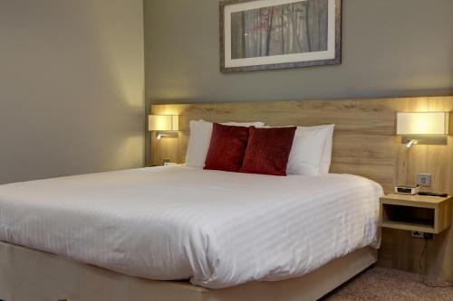 a bedroom with a large white bed with red pillows at Linton Lodge a BW Signature Collection Hotel in Oxford