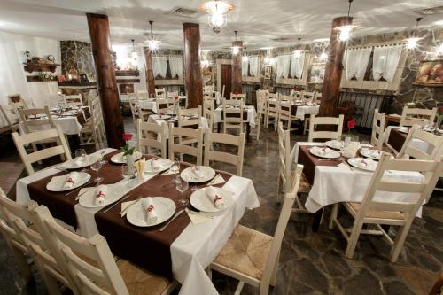 a dining room with white tables and white chairs at Hotel Helen in Bacău
