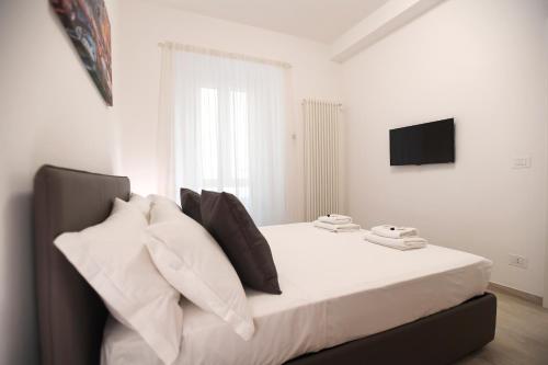 ein Schlafzimmer mit einem weißen Bett mit Kissen und einem TV in der Unterkunft LATERANO 250 - COLOSSEO in Rom