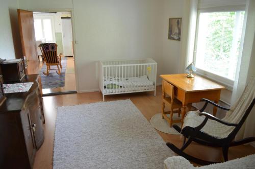 a living room with a crib and a table with a chair at Luntinmäen omakotitalo in Keskikylä