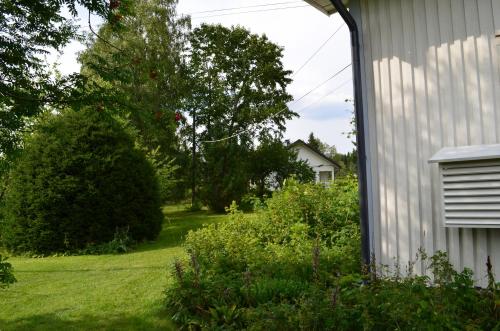 a yard next to a white house with a tree at Luntinmäen omakotitalo in Keskikylä