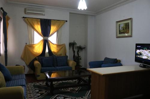 a living room with blue chairs and a television at Dynasty Suite in Aley