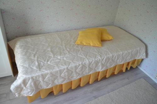 a bed with a yellow pillow on top of it at Luntinmäen omakotitalo in Keskikylä