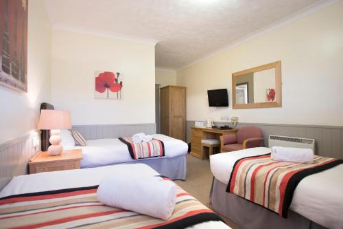 a hotel room with three beds and a desk at Breckland Lodge in Attleborough