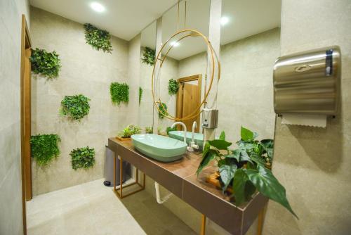 een badkamer met een wastafel, een spiegel en planten bij Hotel Union in Podgorica