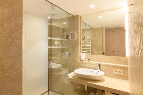a bathroom with a sink and a glass shower at Hotel Montafoner Hof in Schruns-Tschagguns