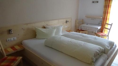a bed with white sheets and pillows in a room at Haus Bergheim in Sankt Leonhard im Pitztal