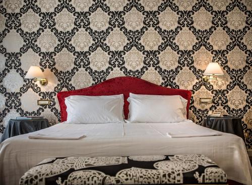 a bedroom with a bed with a red headboard and wallpaper at Regina Adelaide Hotel & SPA in Garda