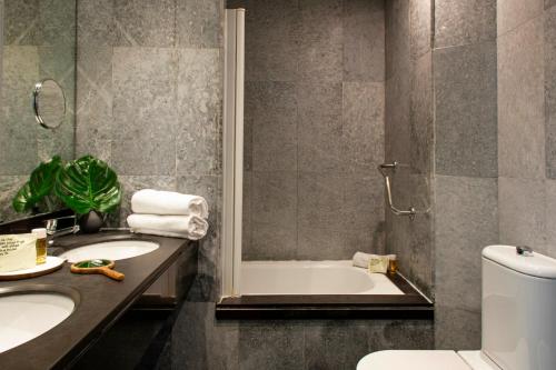 a bathroom with a tub and two sinks and a toilet at Chic & Basic Velvet in Barcelona