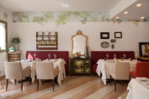 a restaurant with white tables and chairs and a mirror at Regina Adelaide Hotel & SPA in Garda