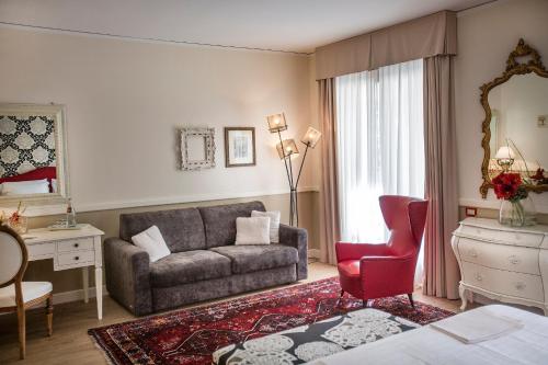 a living room with a couch and a red chair at Regina Adelaide Hotel & SPA in Garda