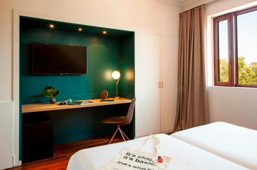 a hotel room with a desk and a tv on a wall at Chic & Basic Velvet in Barcelona