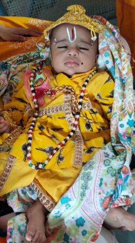 a baby in a yellow outfit laying on its back at Hotel Paramount Palace in Pushkar