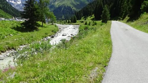 a road next to a river with mountains in the background at Haus Bergheim in Sankt Leonhard im Pitztal