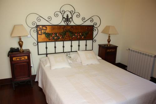 a bedroom with a white bed with a large headboard at Hotel Convento Nossa Senhora do Carmo in Freixinho