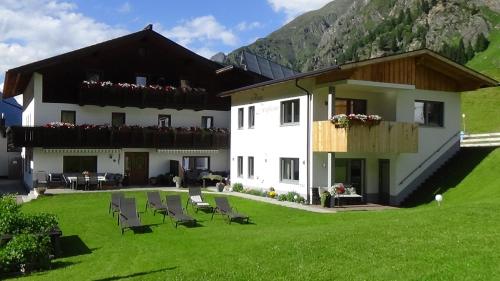 a large white building with chairs in the grass at Haus Bergheim in Sankt Leonhard im Pitztal