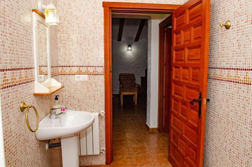 a bathroom with a sink and a wooden door at Casas Rurales Mirador del Mundo in Yeste