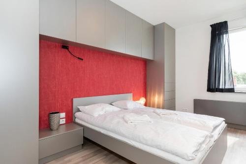 ポズナンにあるModern Apartment Poznań Dąbrowskiegoの赤い壁のベッドルーム1室(大型ベッド1台付)
