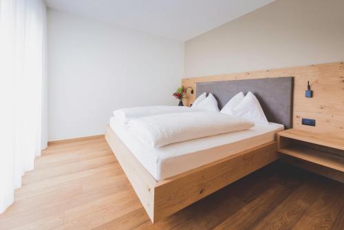 a bedroom with a white bed with a wooden headboard at Sinnergut in Nalles