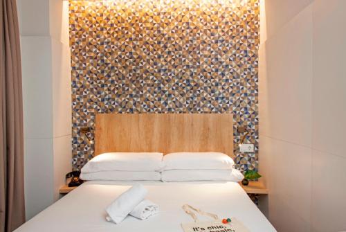 a bed with two pillows and a wall with a pattern at Chic & Basic Velvet in Barcelona