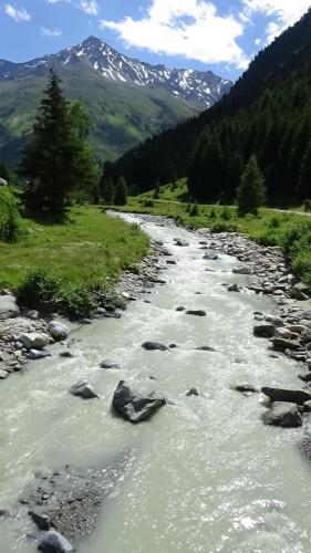 a river with rocks and mountains in the background at Haus Bergheim in Sankt Leonhard im Pitztal