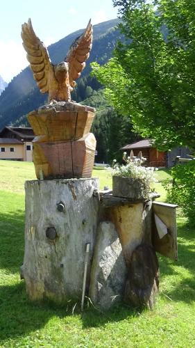 a bird statue sitting on top of a tree stump at Haus Bergheim in Sankt Leonhard im Pitztal