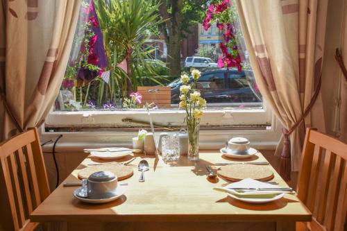a wooden table with plates and utensils in front of a window at Shearwater in Bridlington