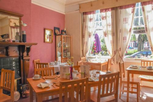 a dining room with a table and chairs and two windows at Shearwater in Bridlington