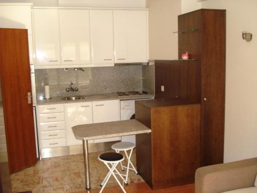 a kitchen with white cabinets and a counter with stools at Apartamento T1 - 3min do Santuário in Fátima