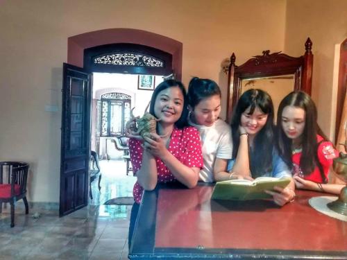 a group of girls sitting at a table with a book at Old Parkland Hostel in Galle